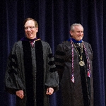 Two faculty members smile on stage
